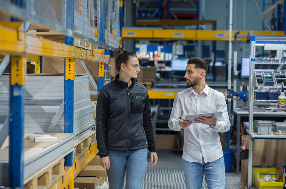 Zwei Mitarbeiter von RAU im Lager bei einer Besprechung – effiziente Arbeitsprozesse und professionelle Teamarbeit in der Produktionslogistik.
