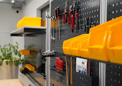 Werkzeughalterung an einer Lochwand mit verschiedenen Handwerkzeugen, gelben Aufbewahrungsboxen.