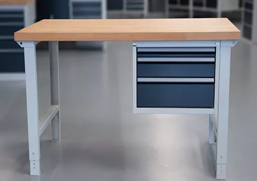 "Einfache Werkbank in modularer Bauweise mit einem Unterbauschrank mit blauen Schubladen und einer robusten Holzplatte, aufgestellt in einer Werkstatthalle.