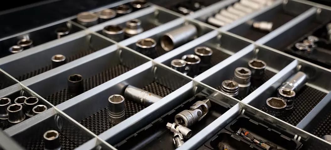 Detailansicht einer Schubladeneinteilung mit verschiedenen Steckschlüsseleinsätzen und Verlängerungen in einer Werkzeugschublade.