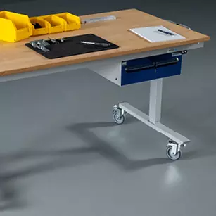 Mobiler Arbeitstisch mit einer Schublade, auf Rollen, ausgestattet mit Werkzeugen, gelben Lagerboxen und Papier auf einer Holzarbeitsplatte.